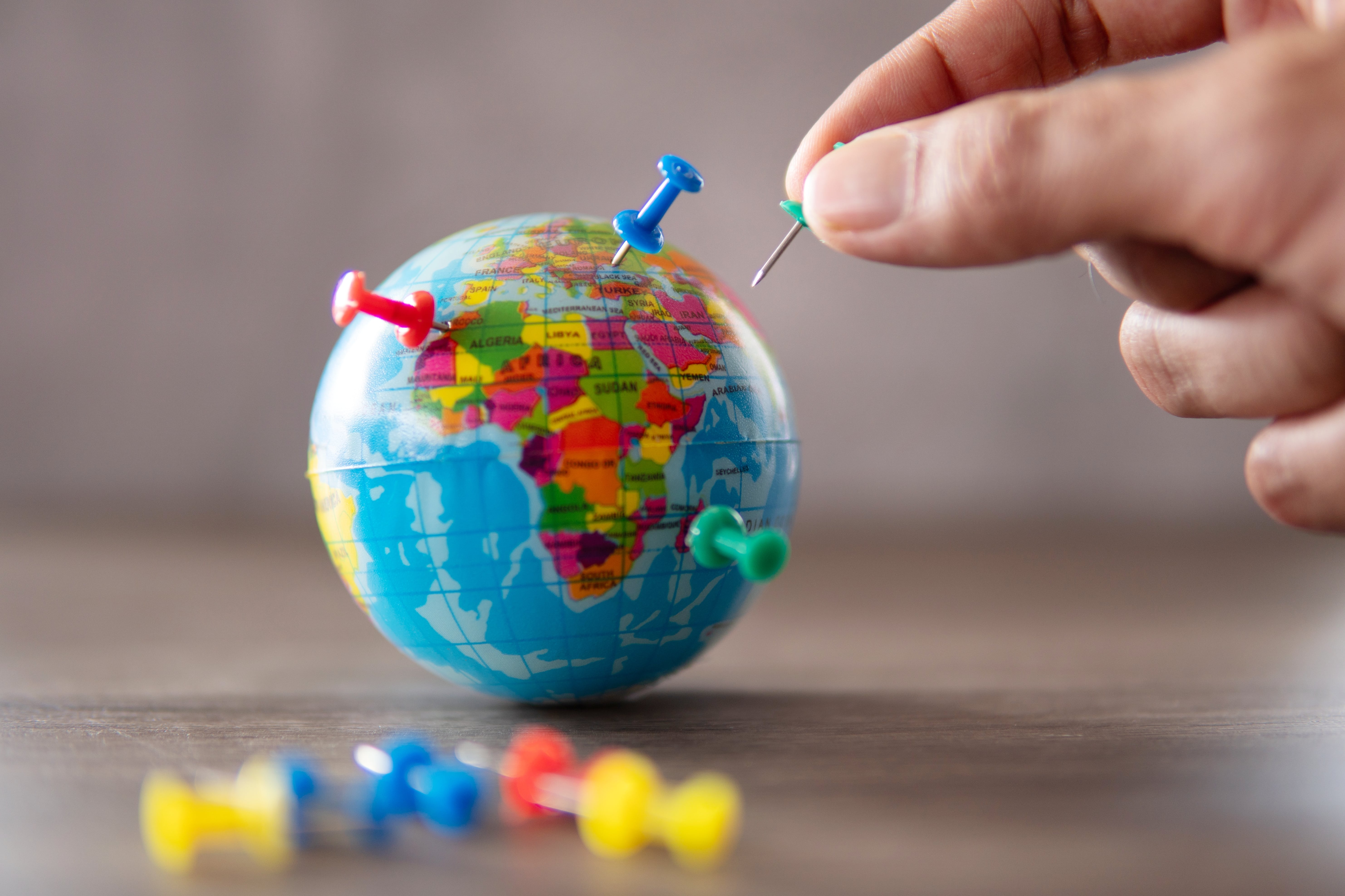 closeup image of hand putting pins on the world globe