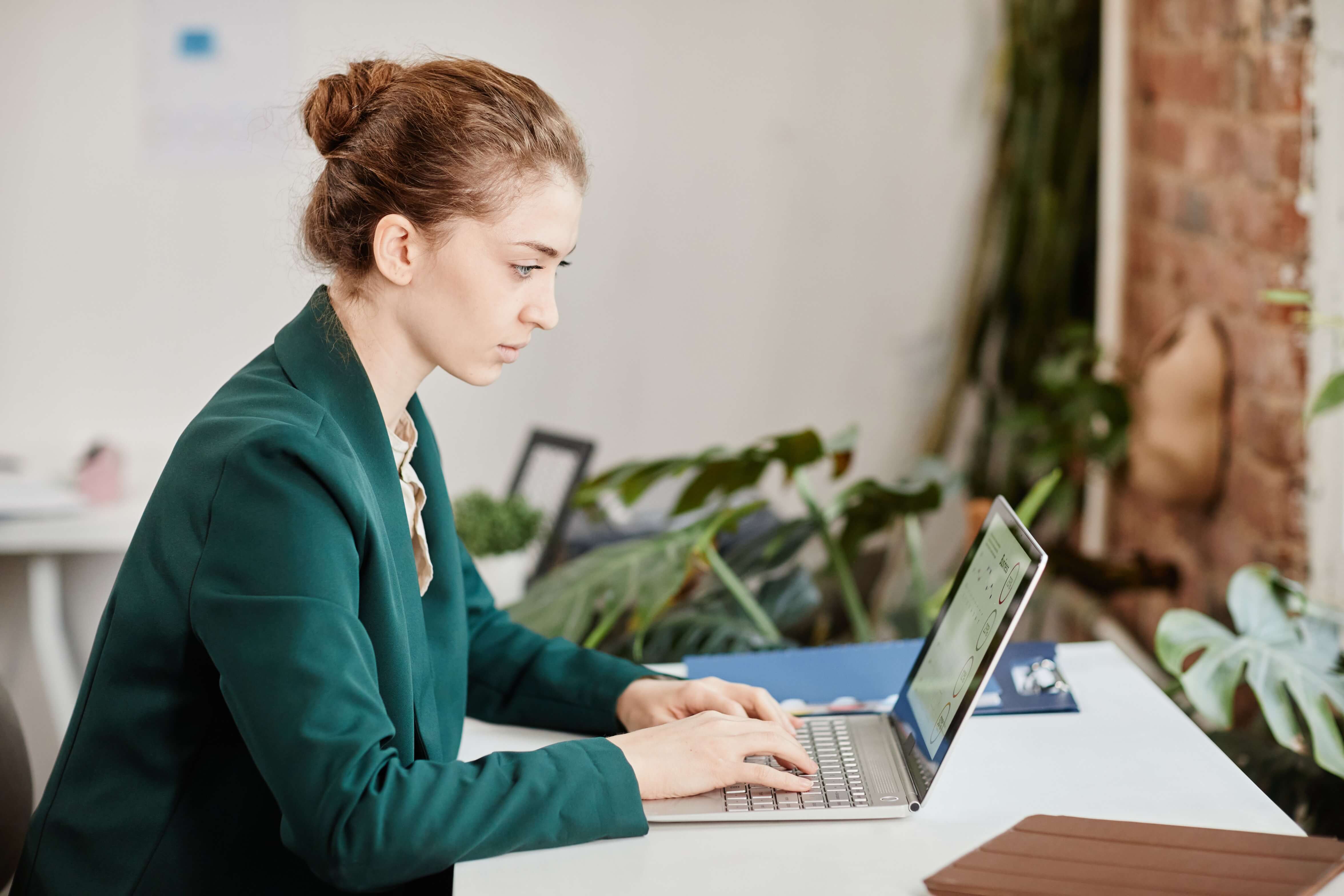 young-pretty-female-employee-looking-at-financial-data-on-laptop-screen