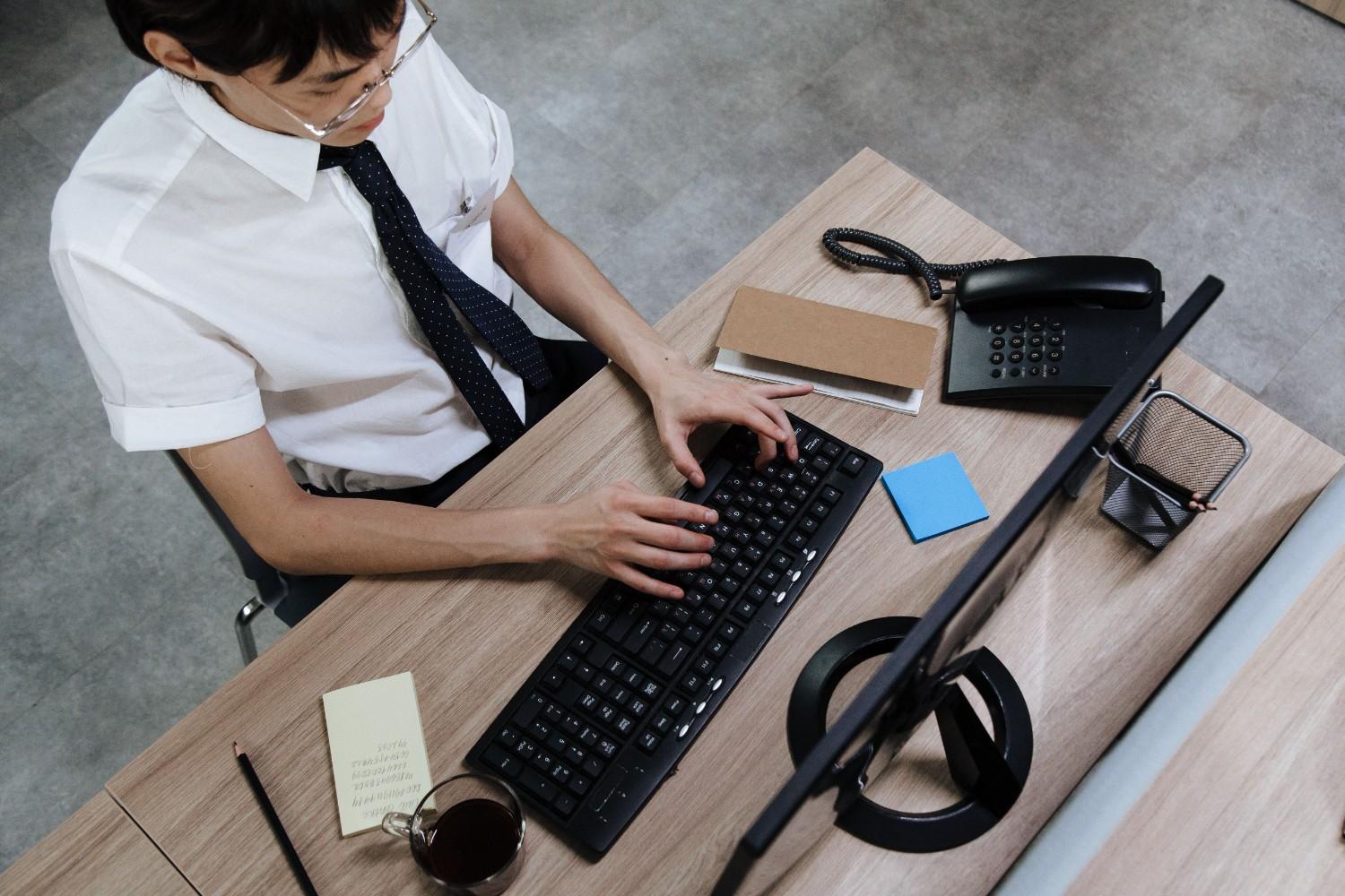 Overhead view office clerk typing on keyboard