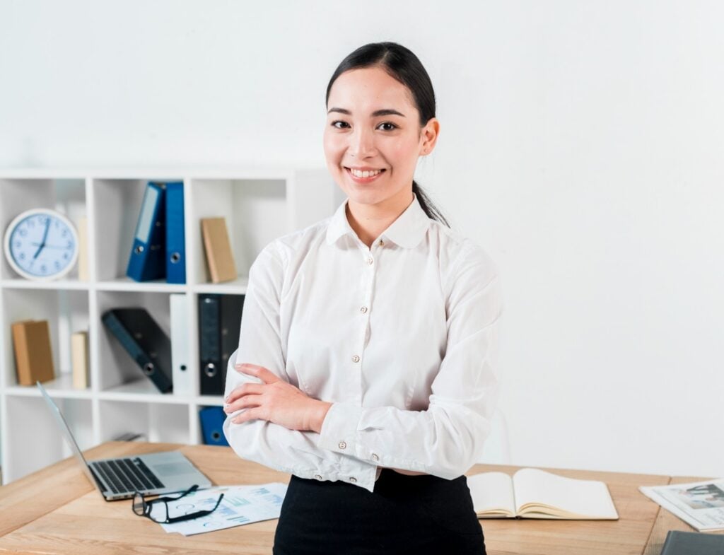 Confident female office manager standing at desk