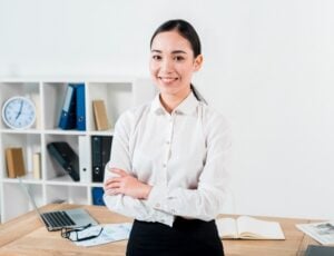 Confident female office manager standing at desk