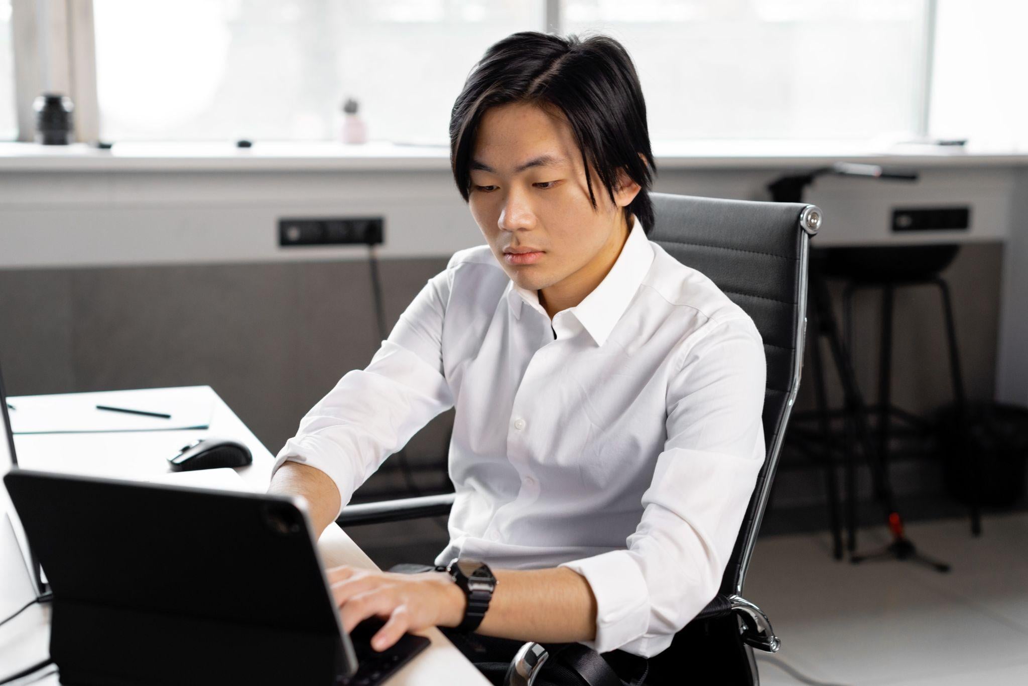 Asian man focused working tablet desk