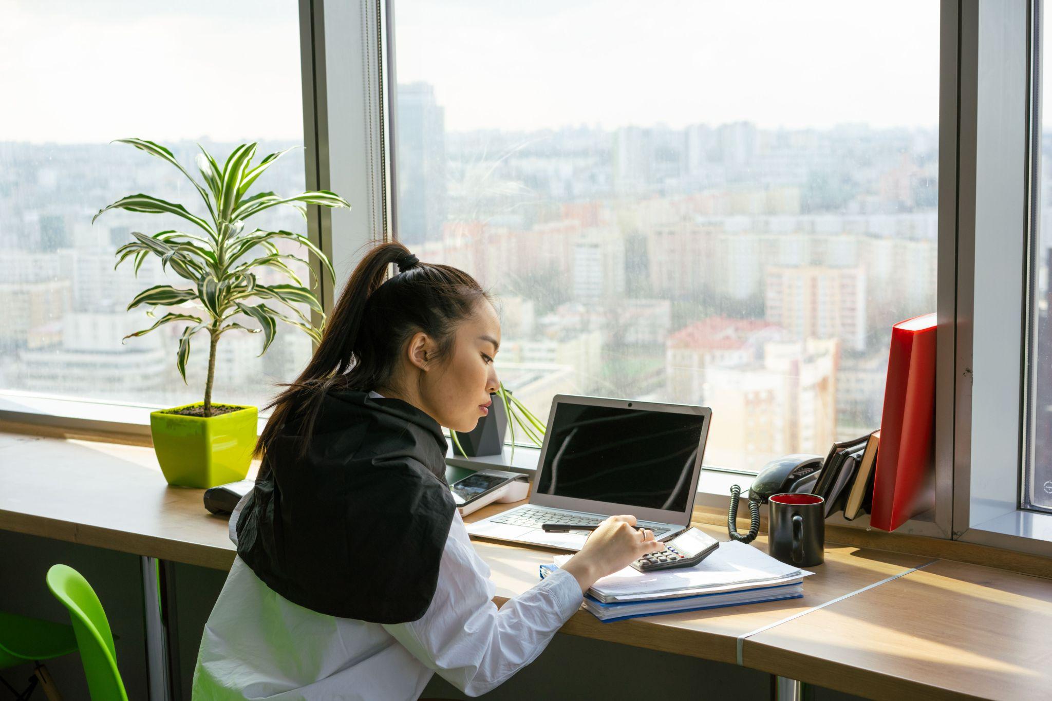 Financial analyst using calculator high rise office