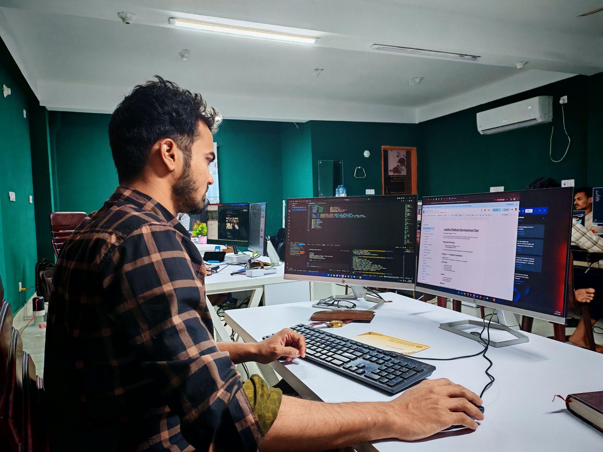Software developer coding dual monitors