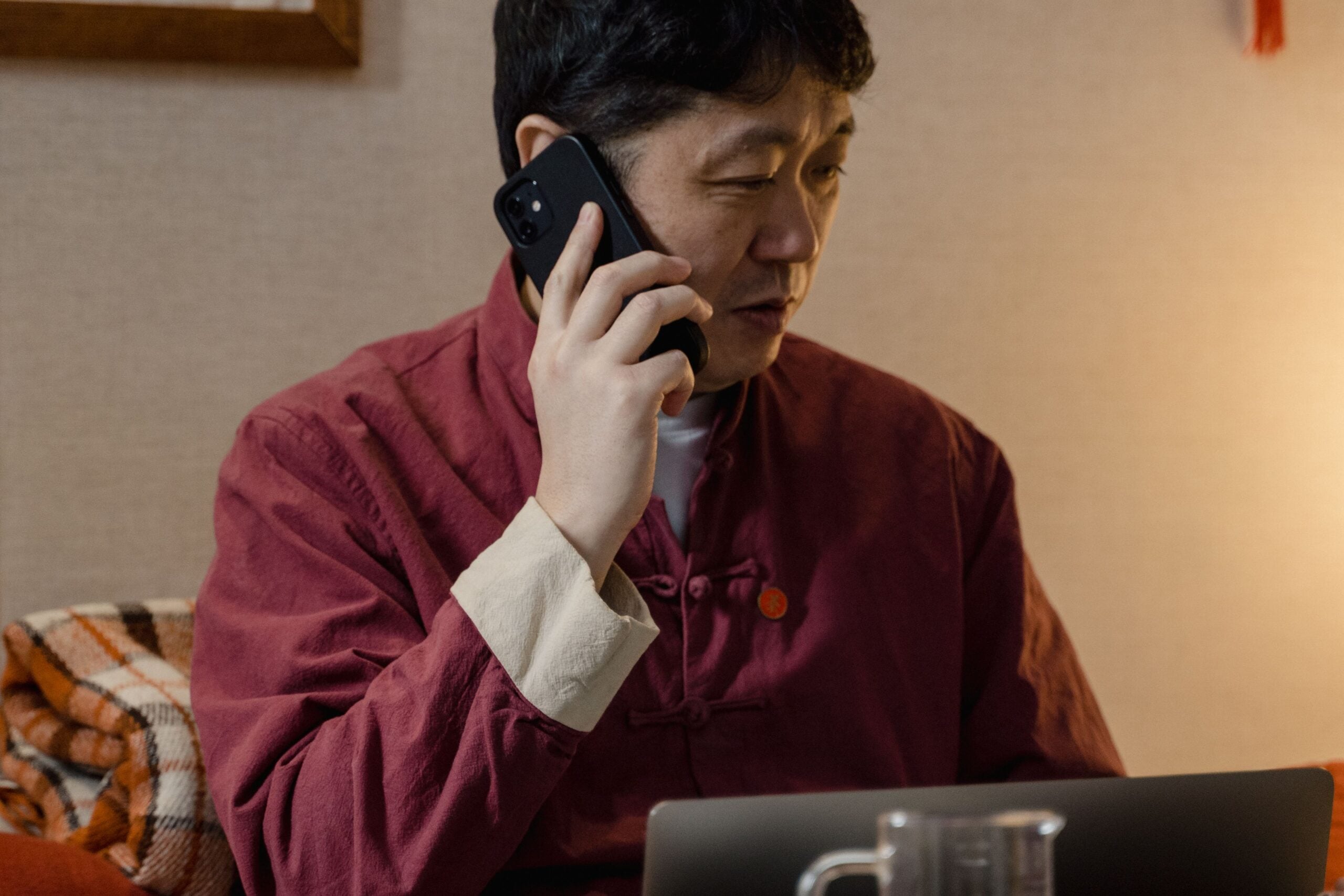 Business owner on a phone call at a laptop while coordinating a campaign launch