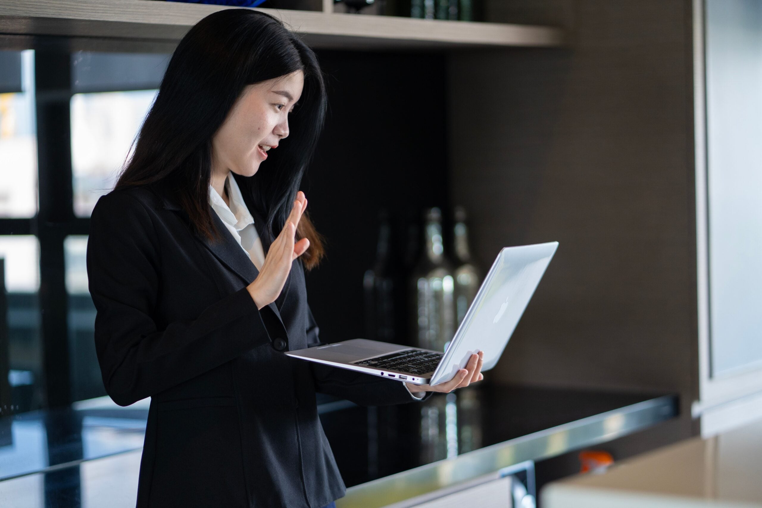 Virtual assistant greeting a client on a video call while holding a laptop