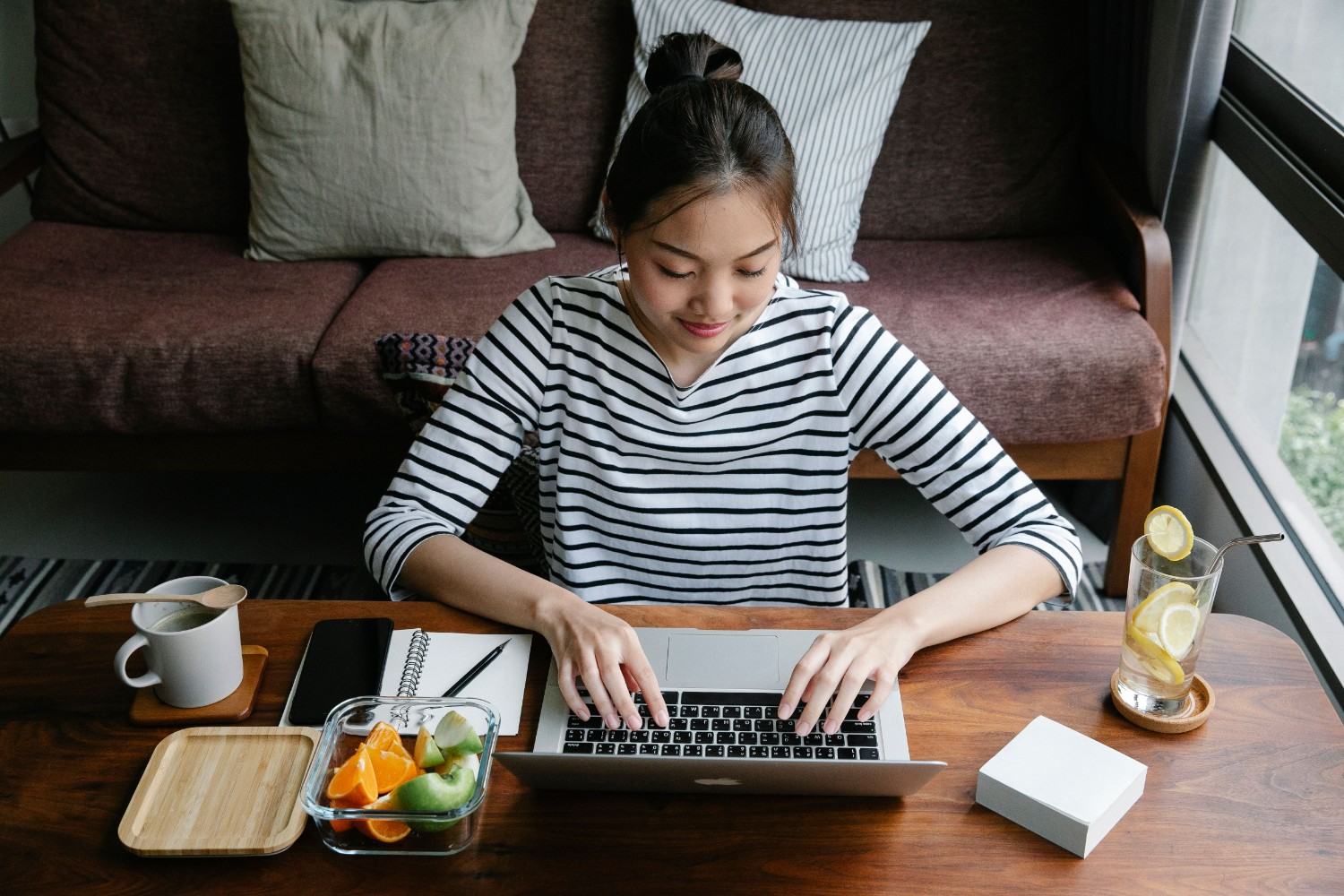 Freelancer typing on laptop with healthy snacks