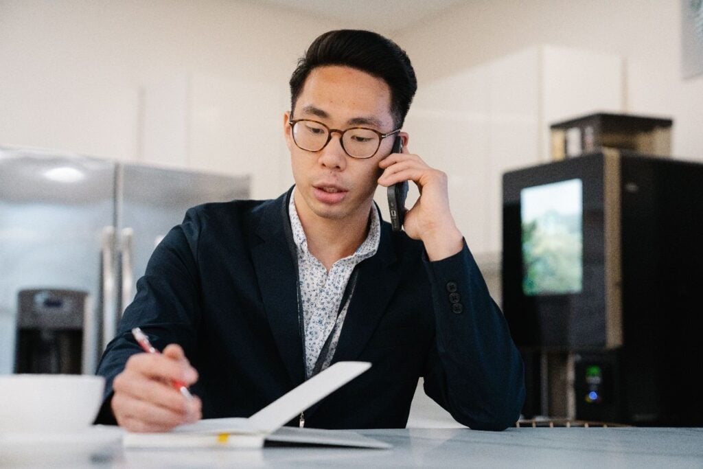 Asian businessman talking on phone taking notes