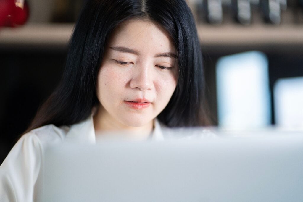 Asian data entry specialist at desk close up
