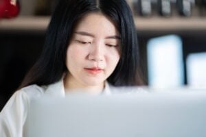 Asian data entry specialist at desk close up