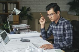 Man reviewing printed plans at his desk while mapping out a new assistant's first weeks