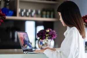 Customer service virtual assistant typing on a laptop at a counter, seen from the side