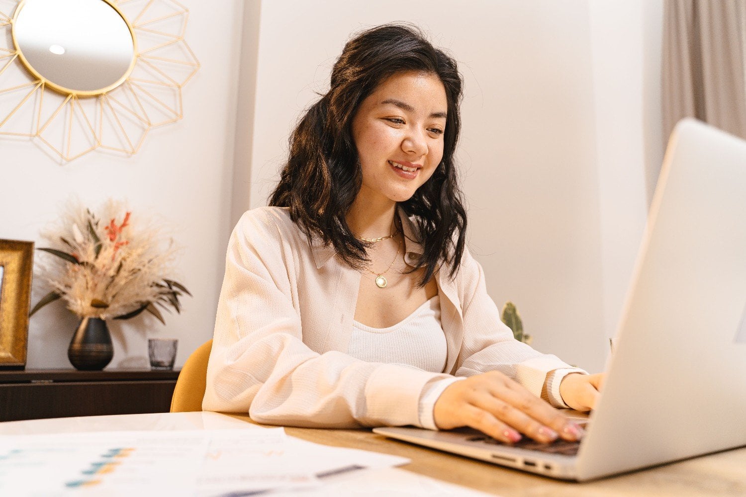 Smiling virtual assistant answering customer messages on a laptop from her home office