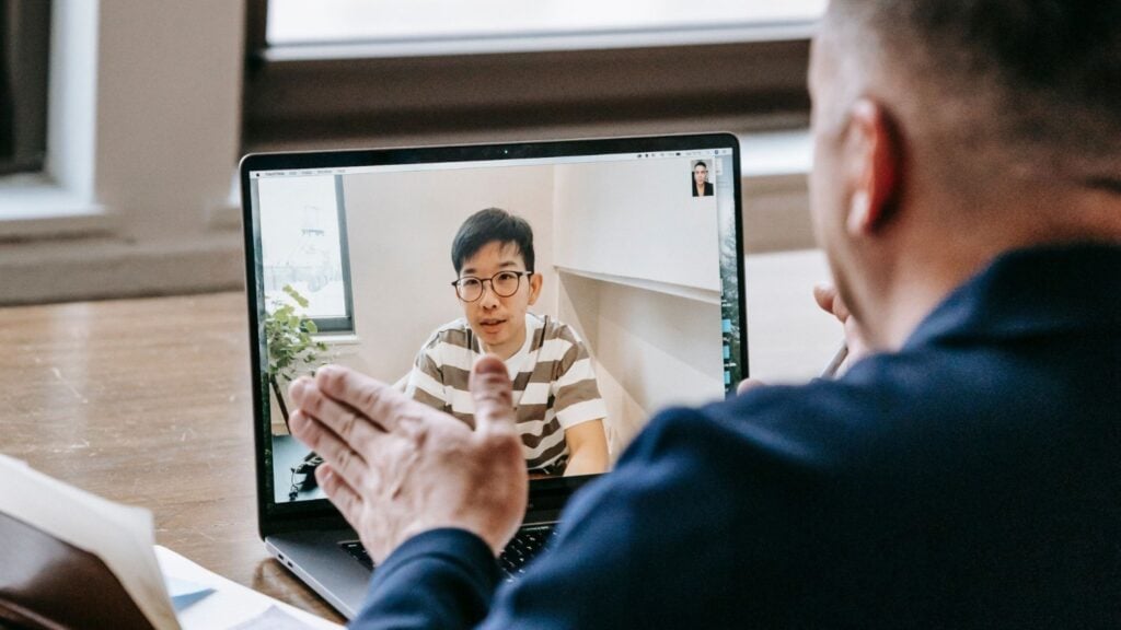 Business owner walking a virtual assistant through a process on a laptop video call