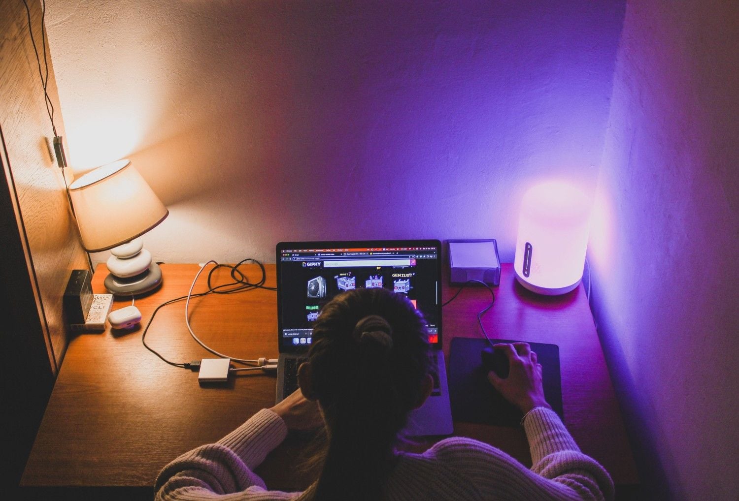 Overhead view of a remote worker at a laptop under lamp light late at night